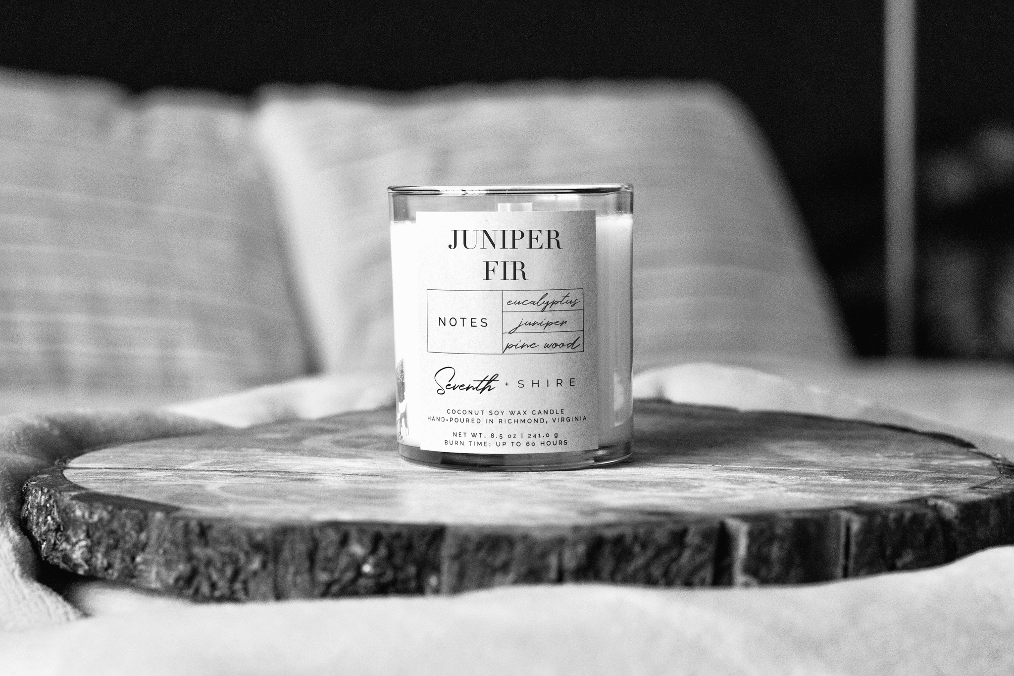Juniper Fir home fragrance candle in glass tumbler jar on bed.
